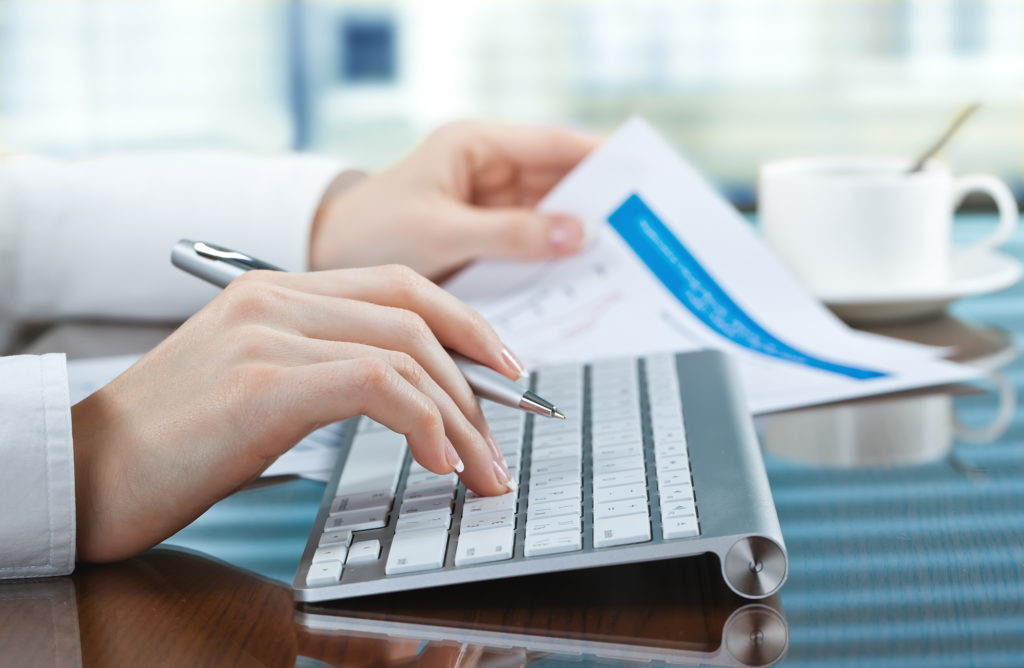 close up of woman's hand on keyboard and paper